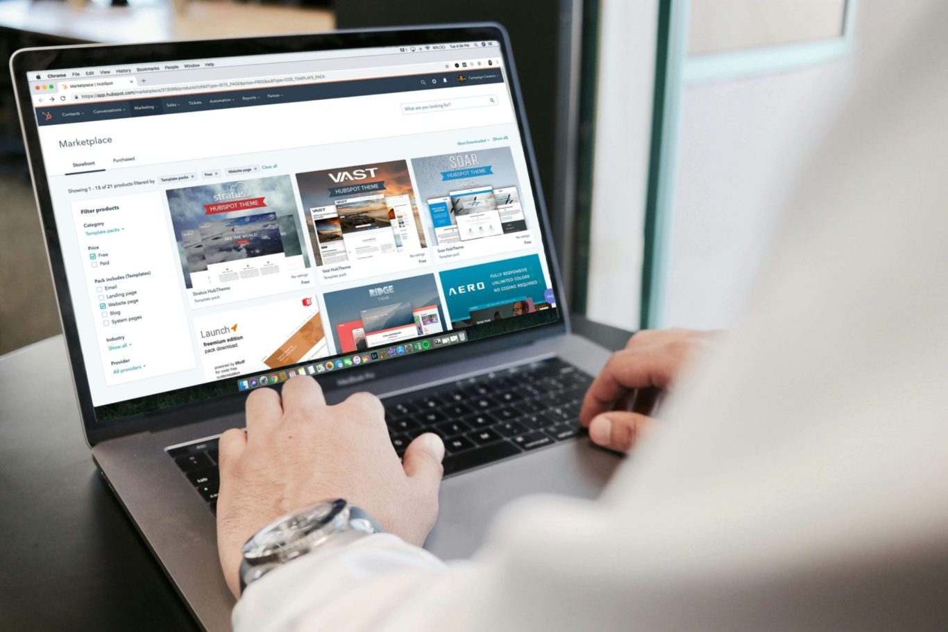 A person browsing a website on a laptop, displaying various content cards.